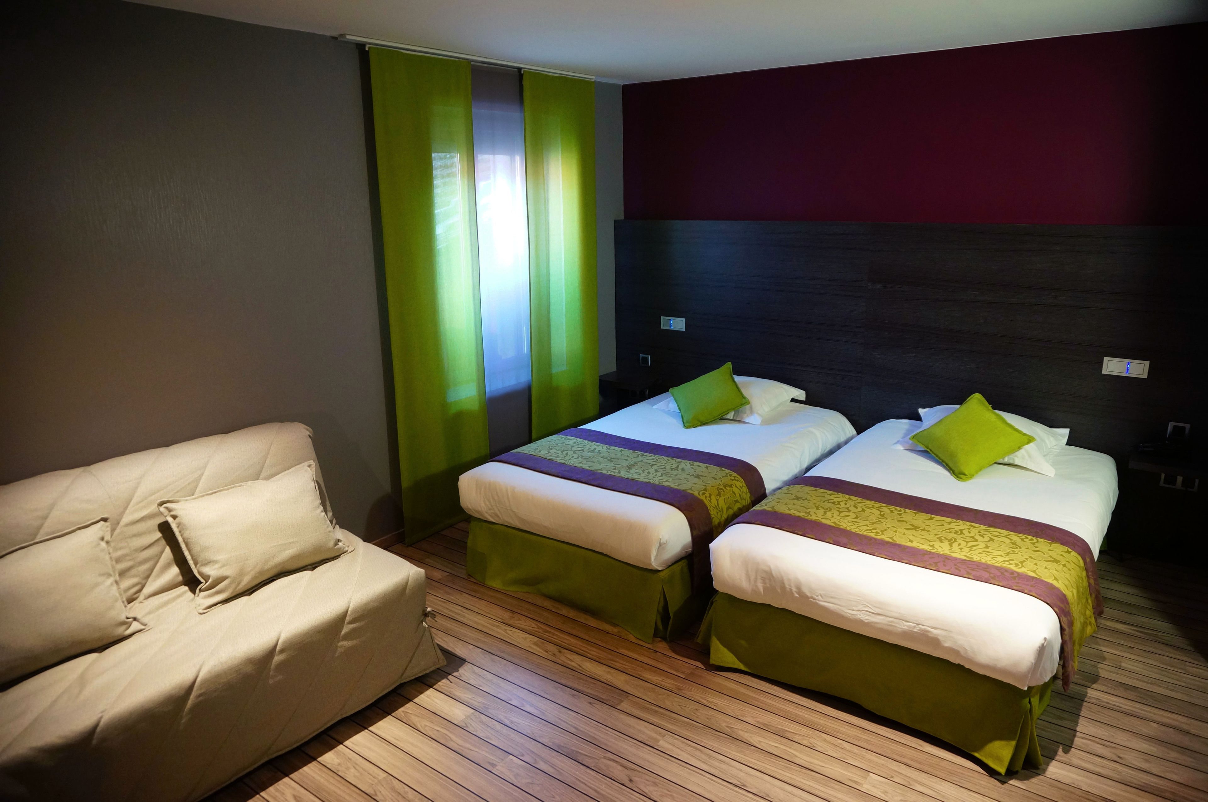 Una habitación de hotel con dos camas, un sofá y una cortina verde.