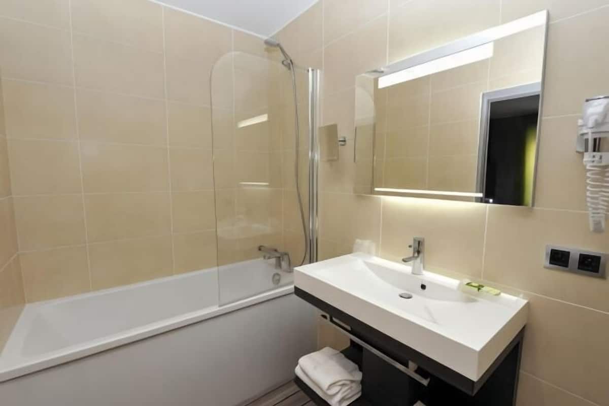 A modern bathroom with a bathtub, a sink, and a mirror.