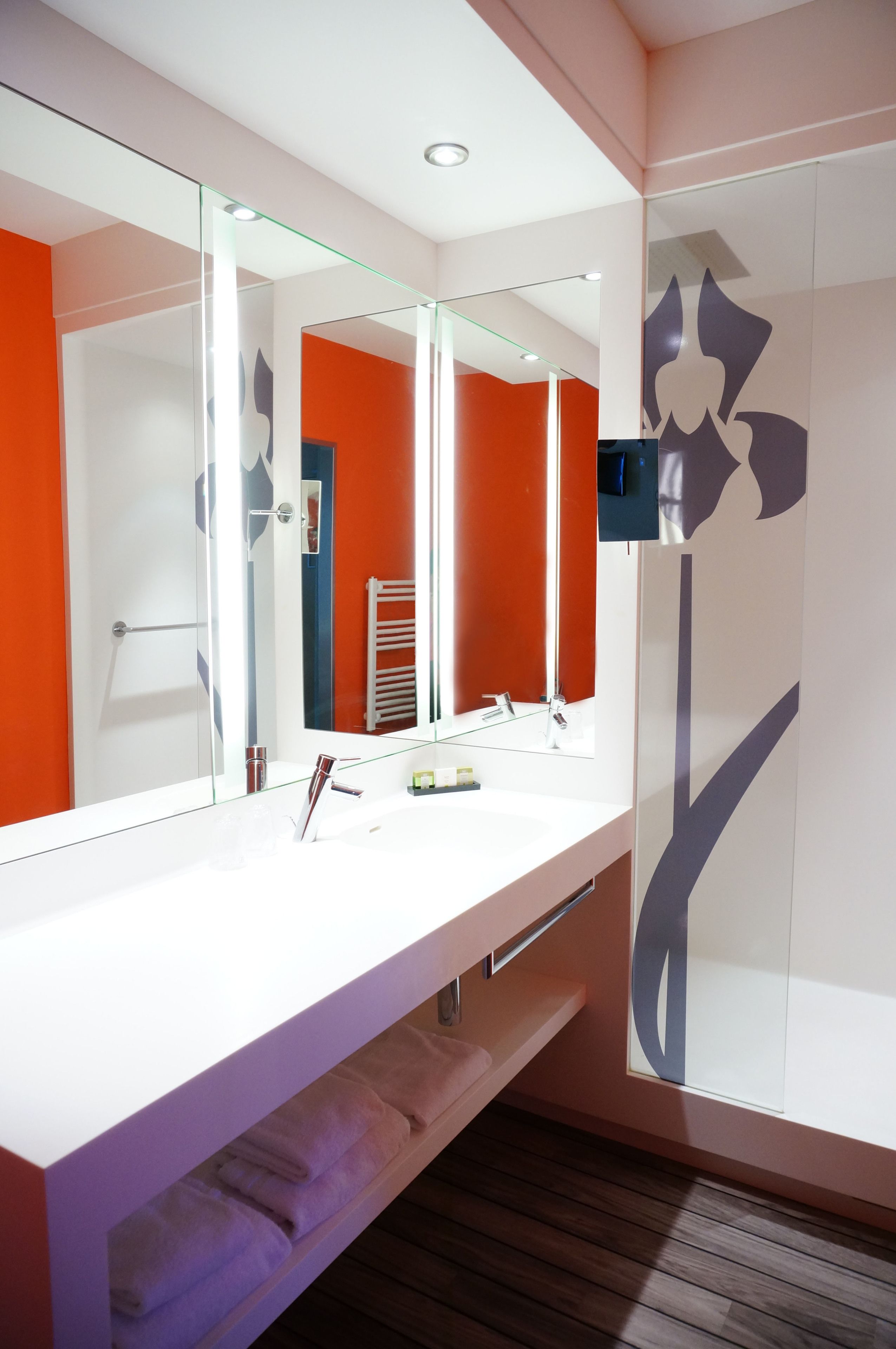 A modern bathroom with a white vanity, a large mirror, and a towel rack.