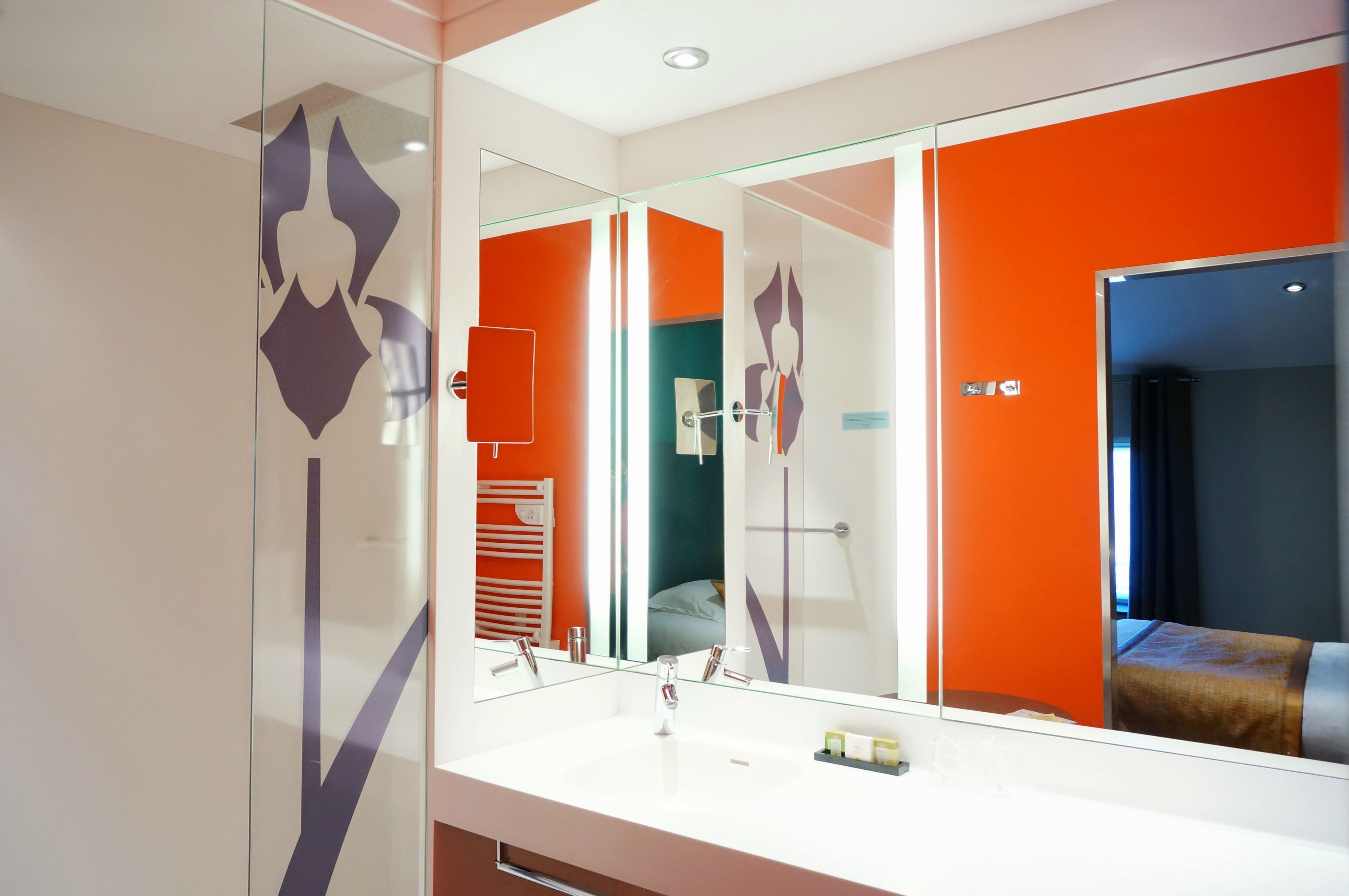Un baño moderno con un espejo grande, un lavabo blanco y un mamparo de vidrio.