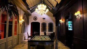 A billiards table in a dimly lit hallway with a chandelier, arched doorways, and wall sconces. - Hôtel de Bourgogne (Macon)