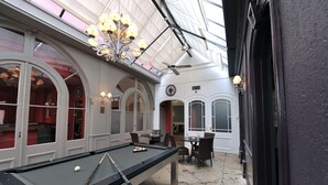 A pool table in a room with arched windows and a chandelier. - Hôtel de Bourgogne (Macon)