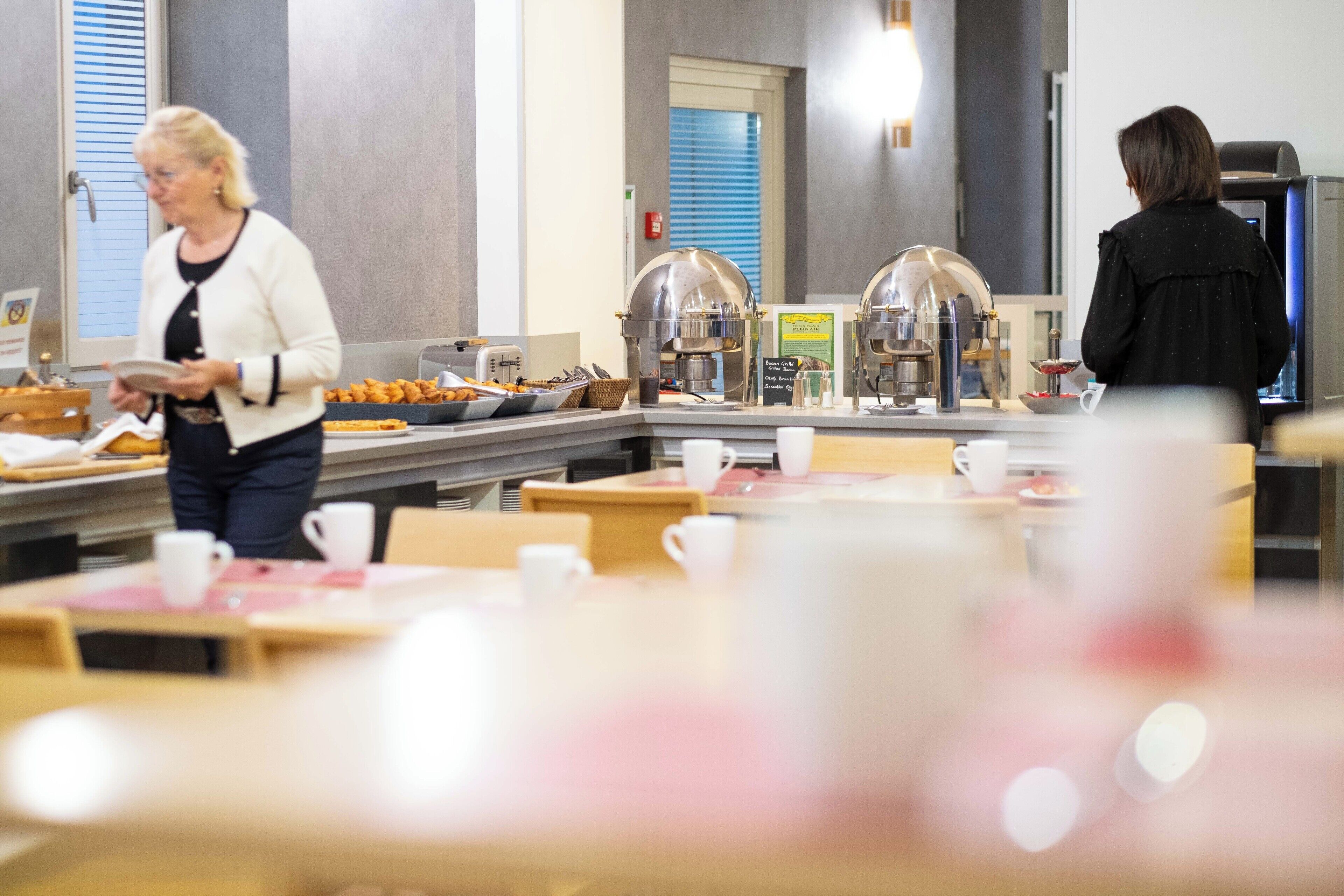 A buffet area with tables and chairs, a coffee station, and a refrigerator.