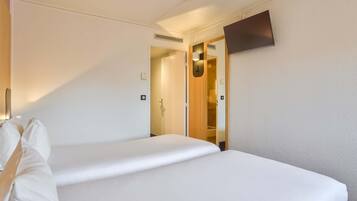 Une chambre d’hôtel avec un lit, un téléviseur fixé au mur et une porte donnant sur un placard.