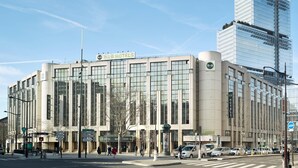 Ein modernes Hotel mit Glasfassade, Beschilderung mit 'B&B HOTELS' und einer Fußgängerampel davor.