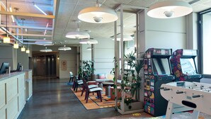Eine moderne Lobby mit Empfangsschalter, Sitzgelegenheiten, Spielautomaten und einem Kicker.
