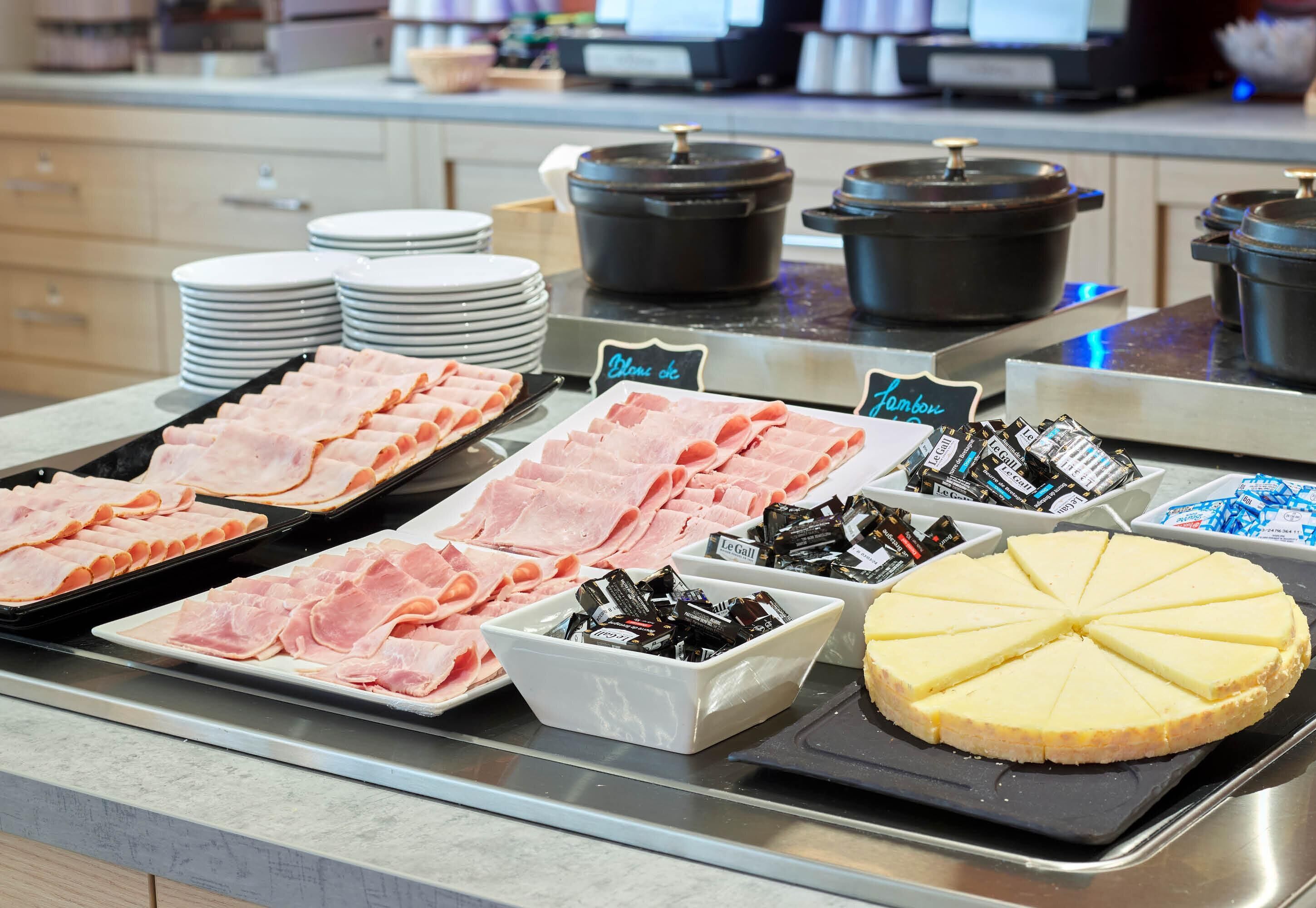 A buffet with various food items including ham, cheese, and condiments.