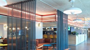 Eine moderne Hotelhalle mit Sitzgelegenheiten, einer Rezeption und einer Bar.