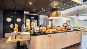 Uma mesa de pequeno-almoço com diversas opções de comida e uma estação de café.