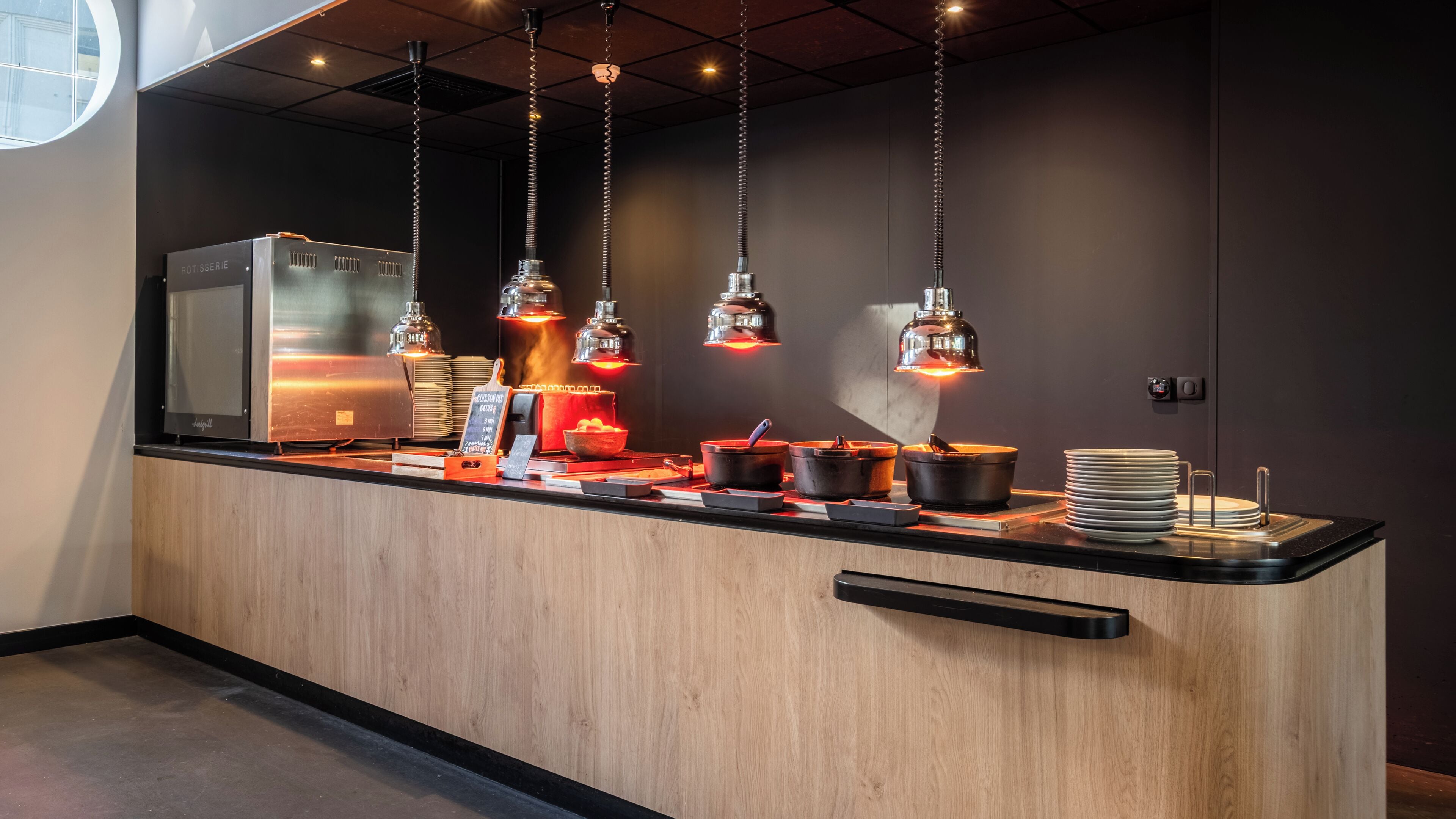 Een moderne keuken met een houten aanrechtblad, hangende吊灯 en een roestvrijstalen afzuigkap.