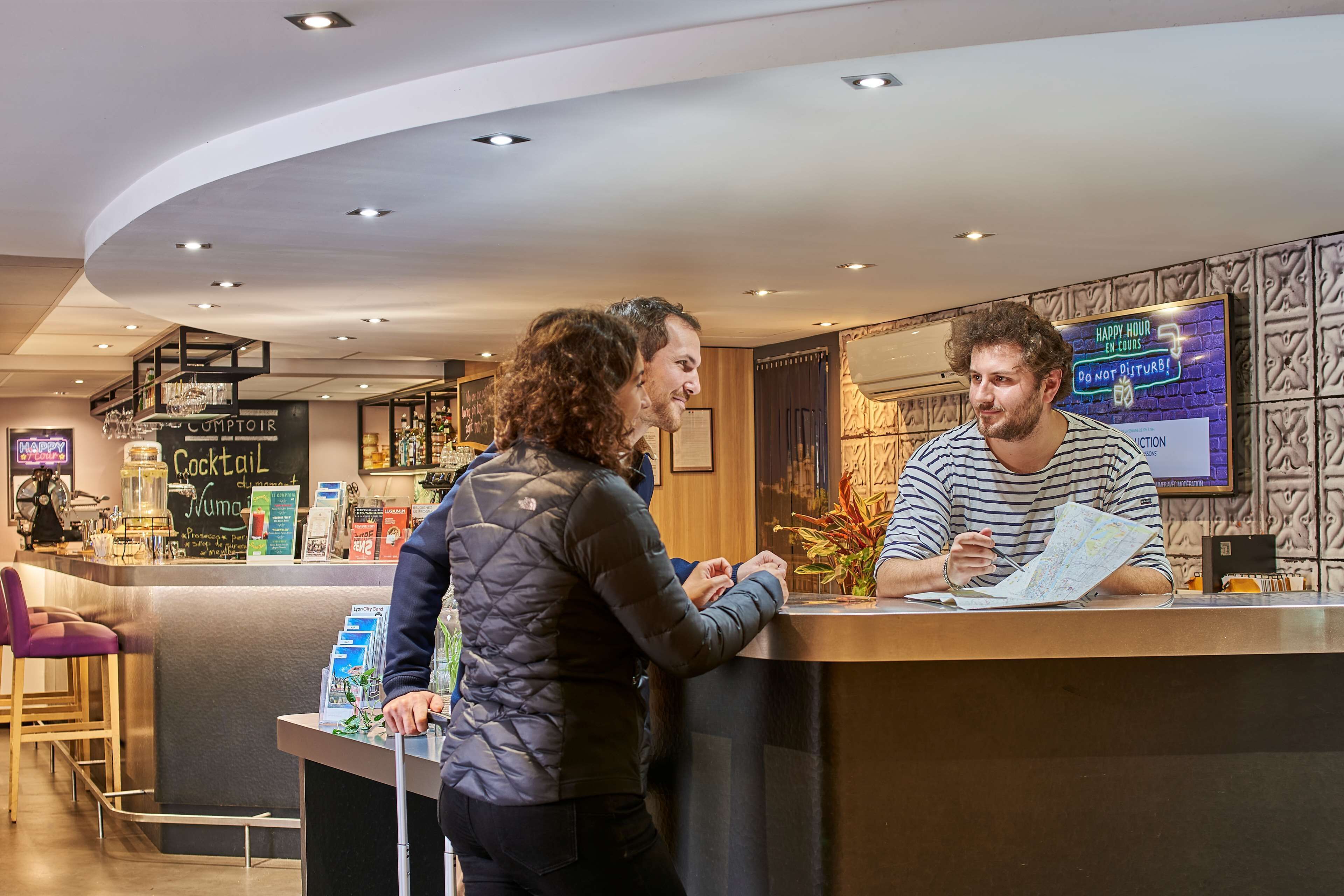 Un comptoir d’accueil dans le hall d’un hôtel moderne, doté d’un plafond incurvé et d’un éclairage encastré.