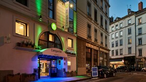 Un hotel con un llamativo letrero de 'Campanile', ventanas amplias y una entrada bien iluminada.