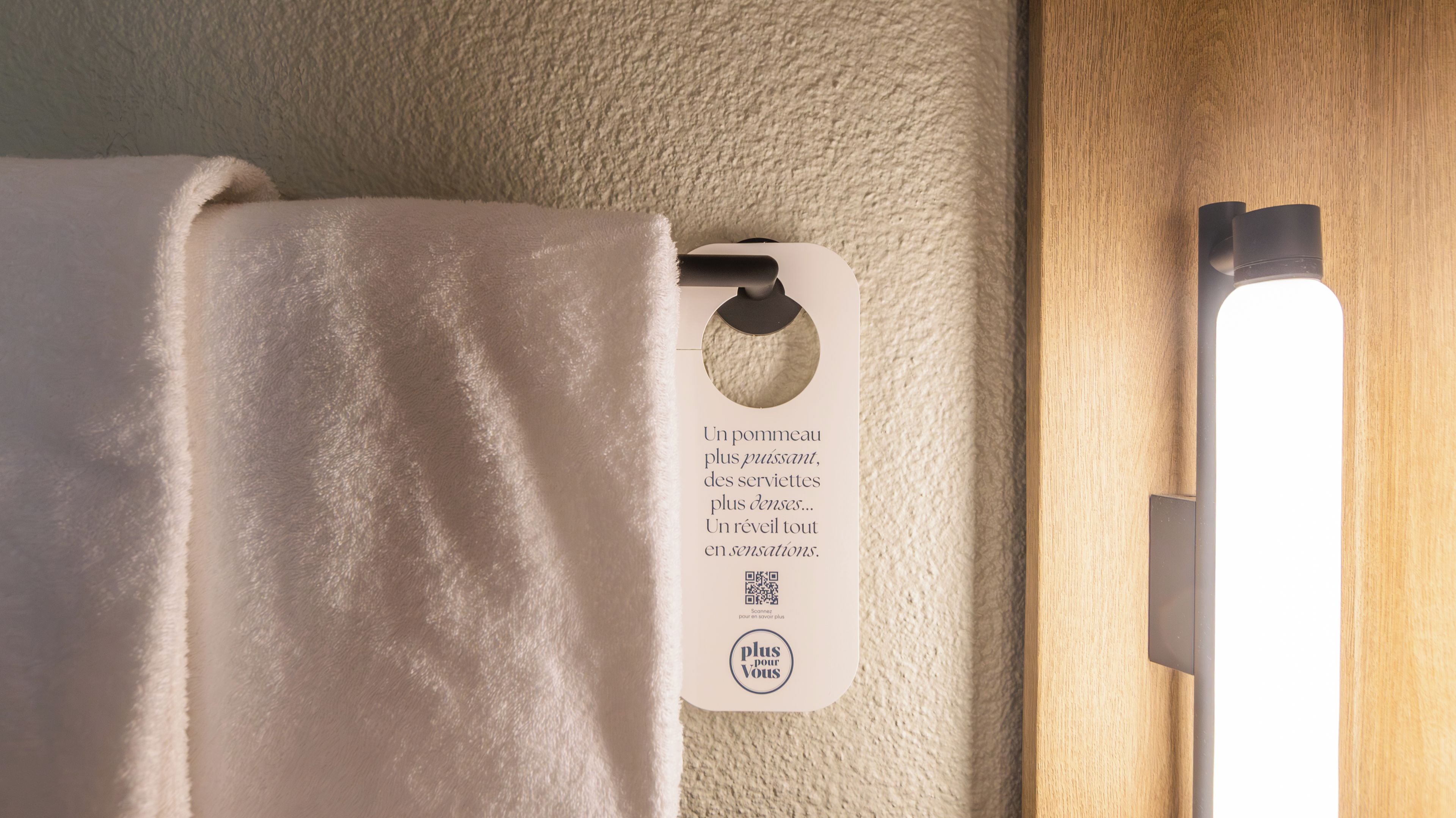 A towel hanging on a textured wall with a tag attached to it.