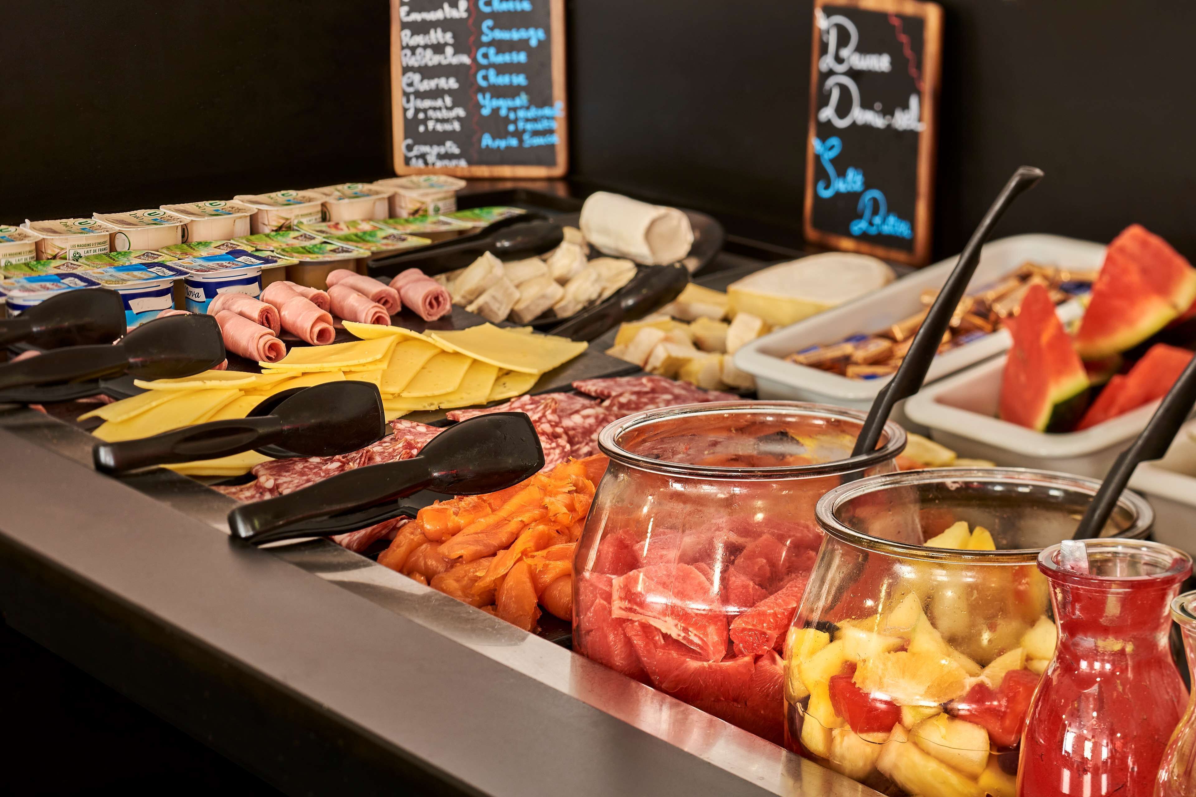 En buffet med et udvalg af madvarer, herunder kød, oste og frugt.