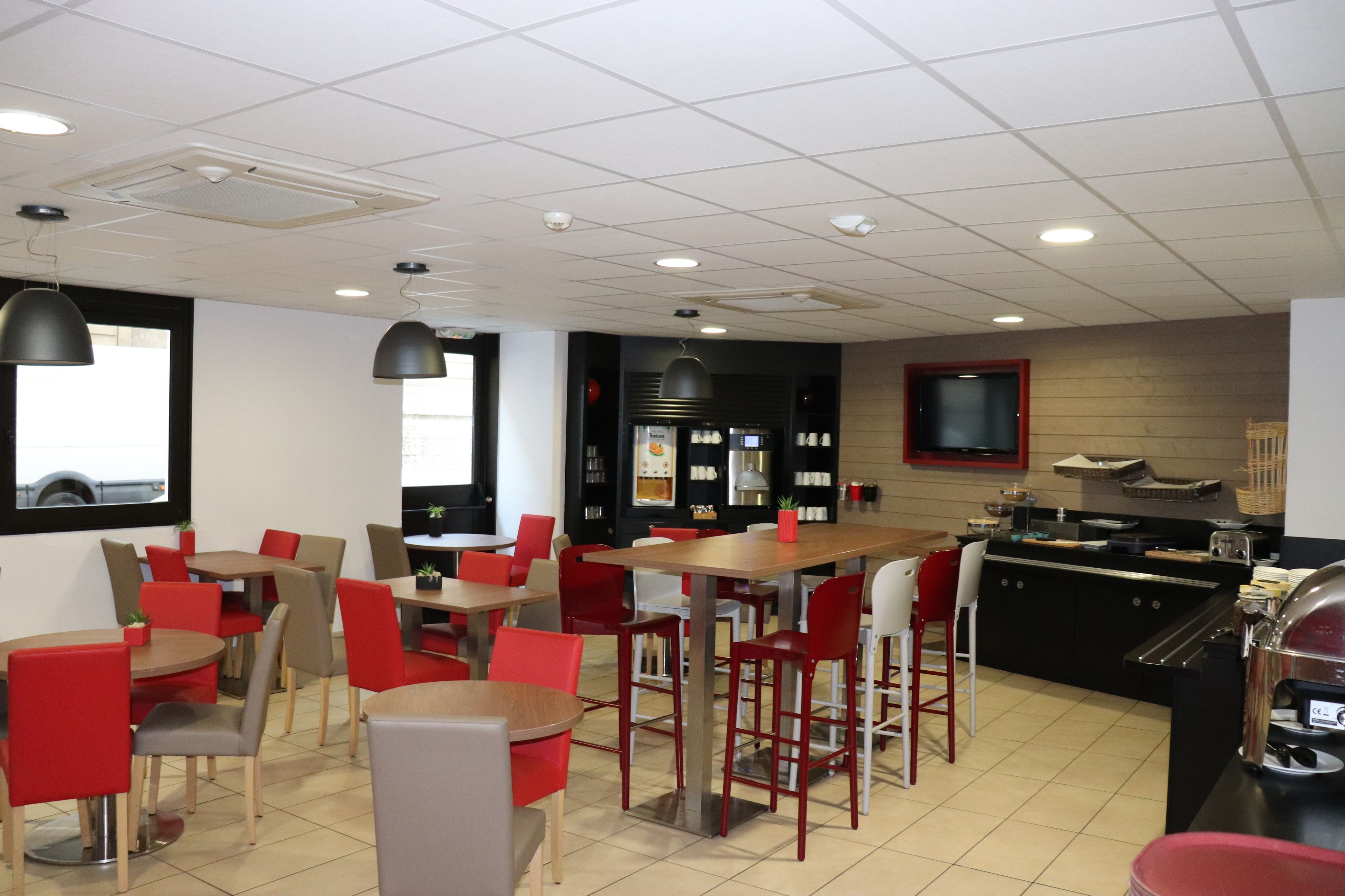 A restaurant with multiple tables and chairs, a kitchen area, and a counter with a grill.