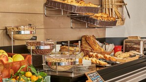 Un bufé con diferentes opciones de comida, entre ellas frutas, pan y pasteles.
