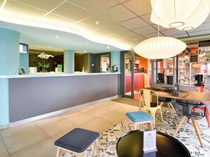 A reception area with a counter, seating, and a patterned floor. - ibis Styles Lyon Confluence (Lyon)