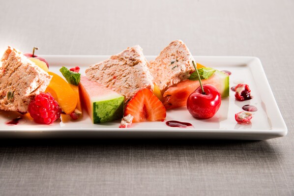 Une assiette rectangulaire blanche sur laquelle on voit différents fruits et une part de gâteau.