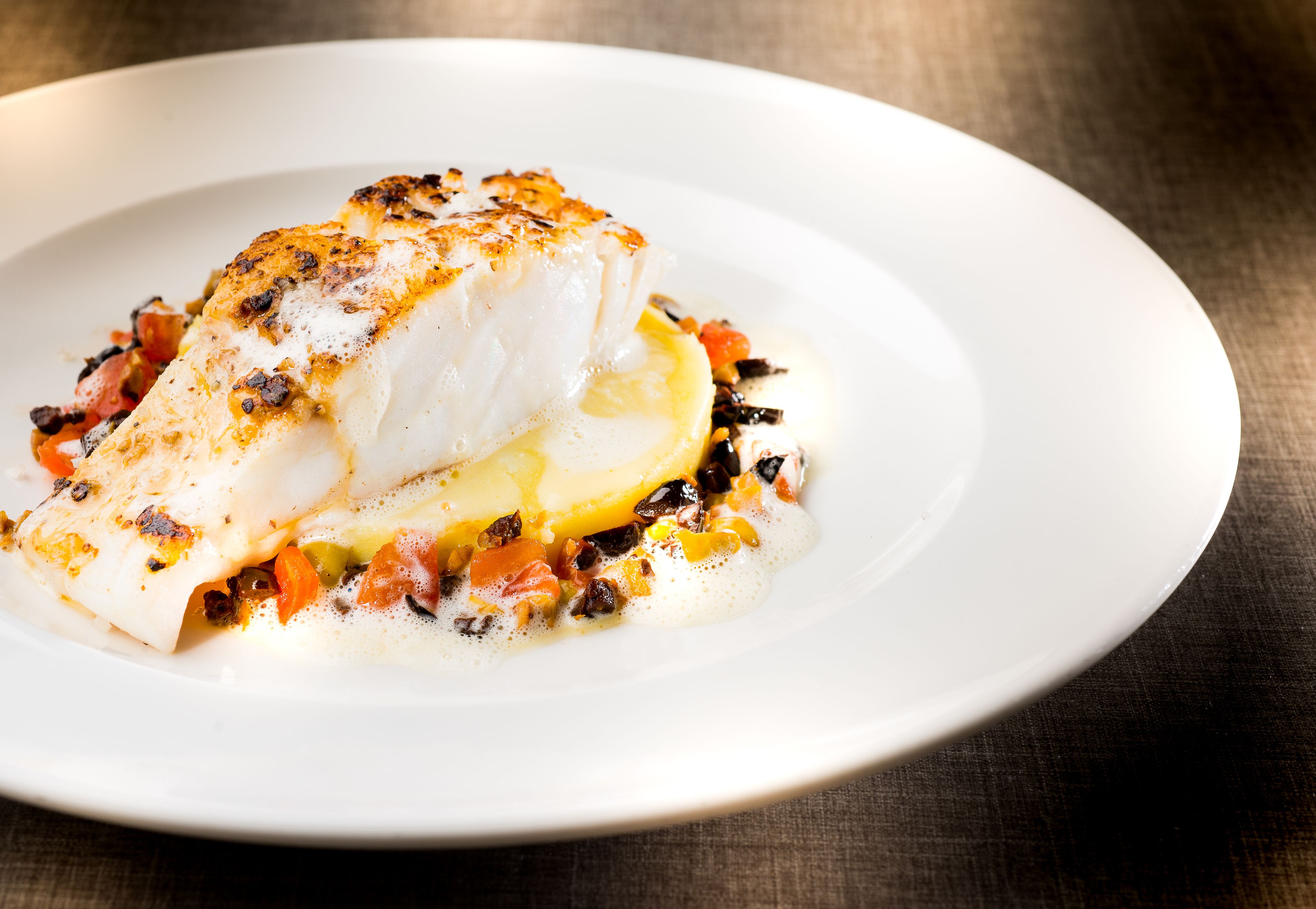 Un plato blanco con un trozo de pescado y verduras.