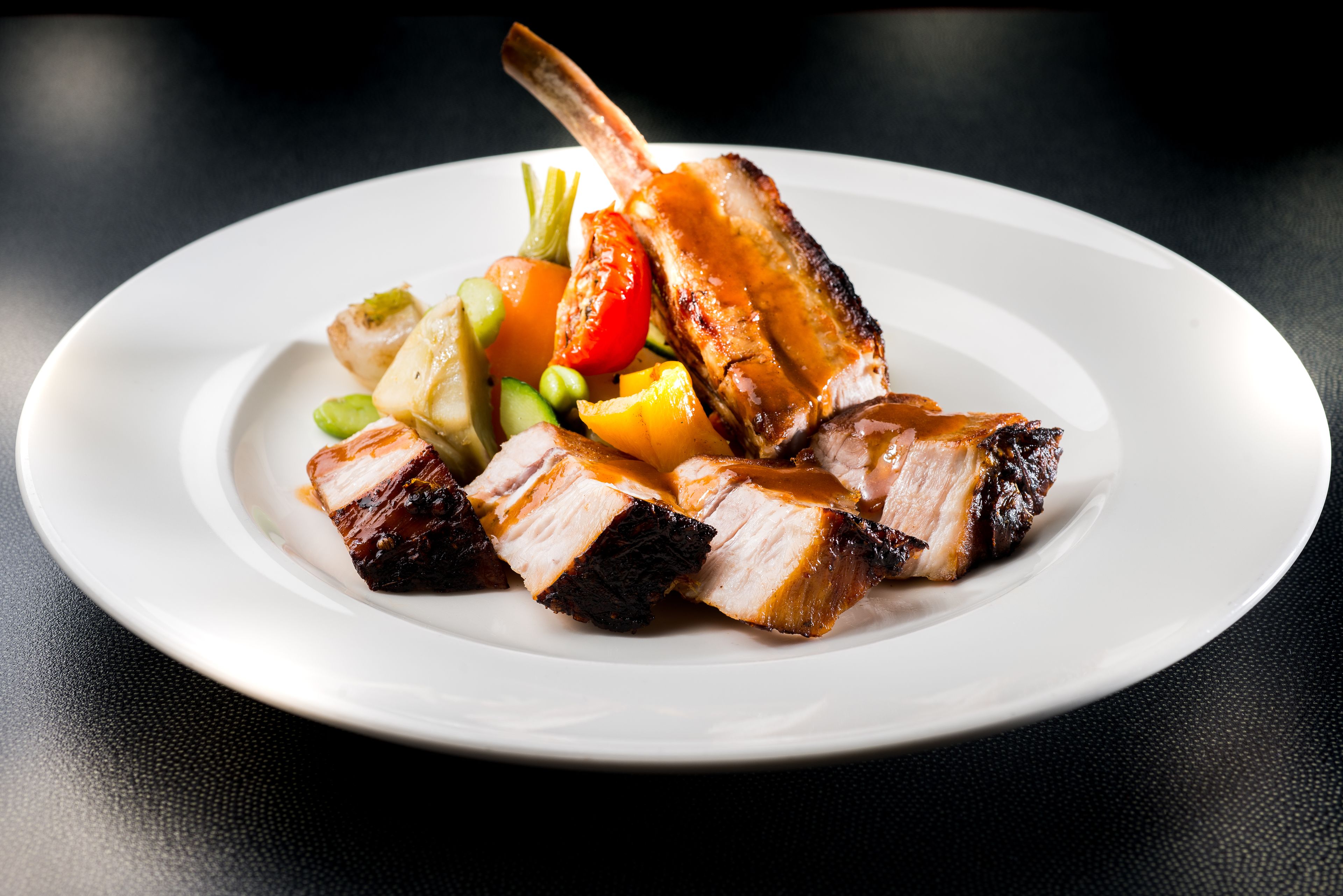 A plate of sliced meat with vegetables.