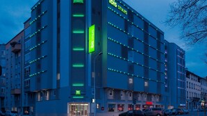 A multi-story hotel with a modern design, featuring a prominent 'ibis Styles' sign, a glass entrance, and a parking area visible in front. - ibis Styles Lyon Confluence (Lyon)