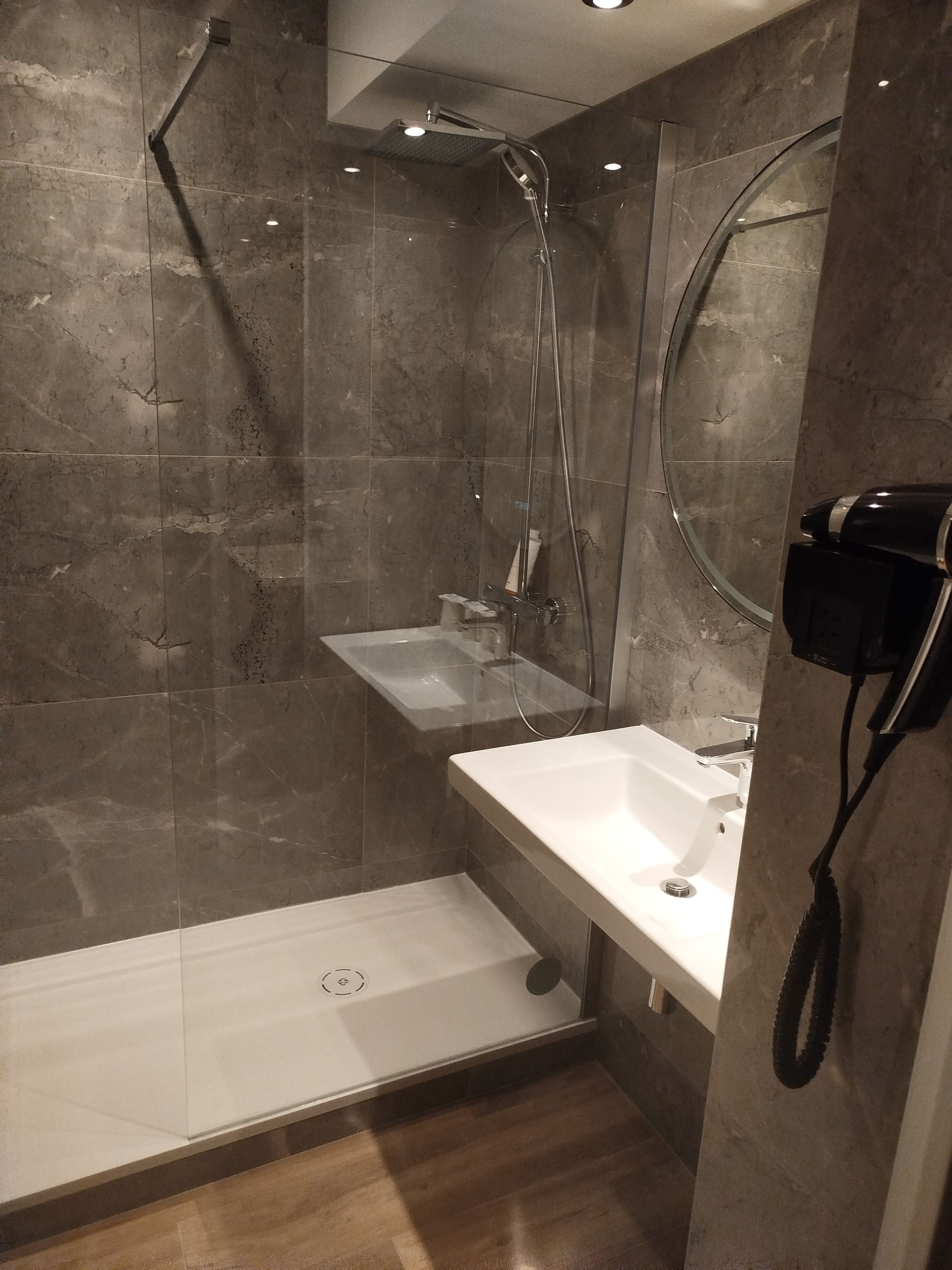 A modern bathroom with a glass-enclosed shower, a white sink, and a mirror.