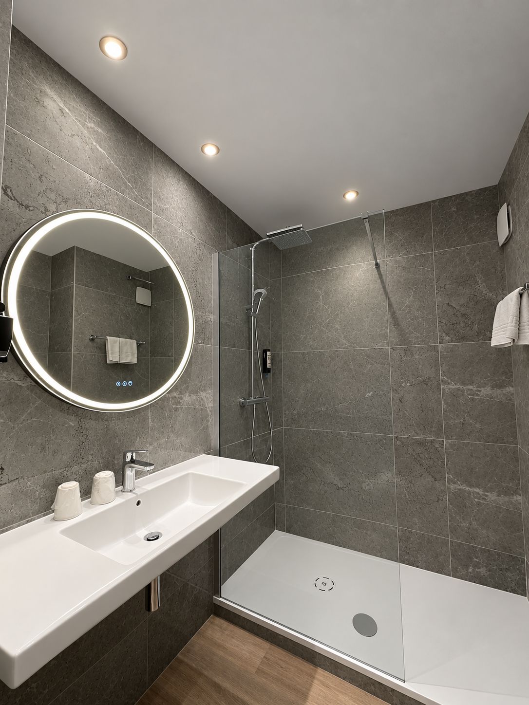 A modern bathroom with a large mirror, a shower, and a sink.