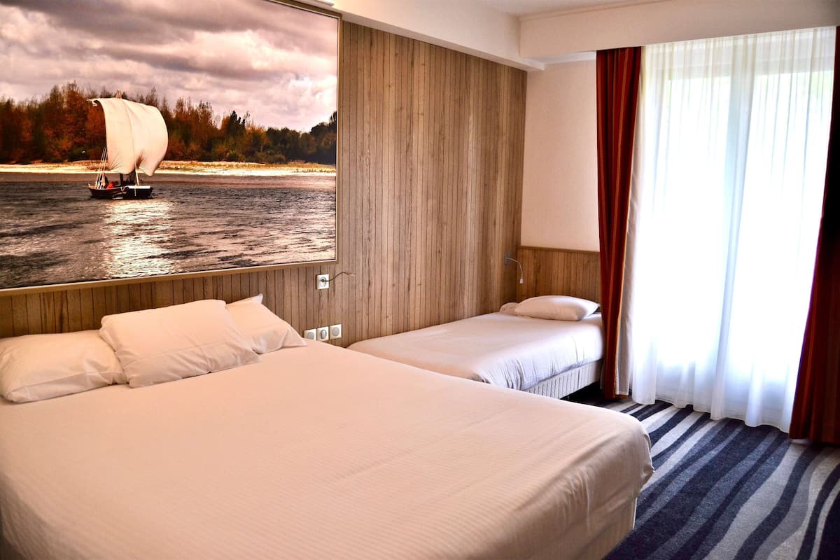 Una habitación de hotel con dos camas, un ventanal con cortinas, una pared de madera y un cuadro de un velero en la pared.