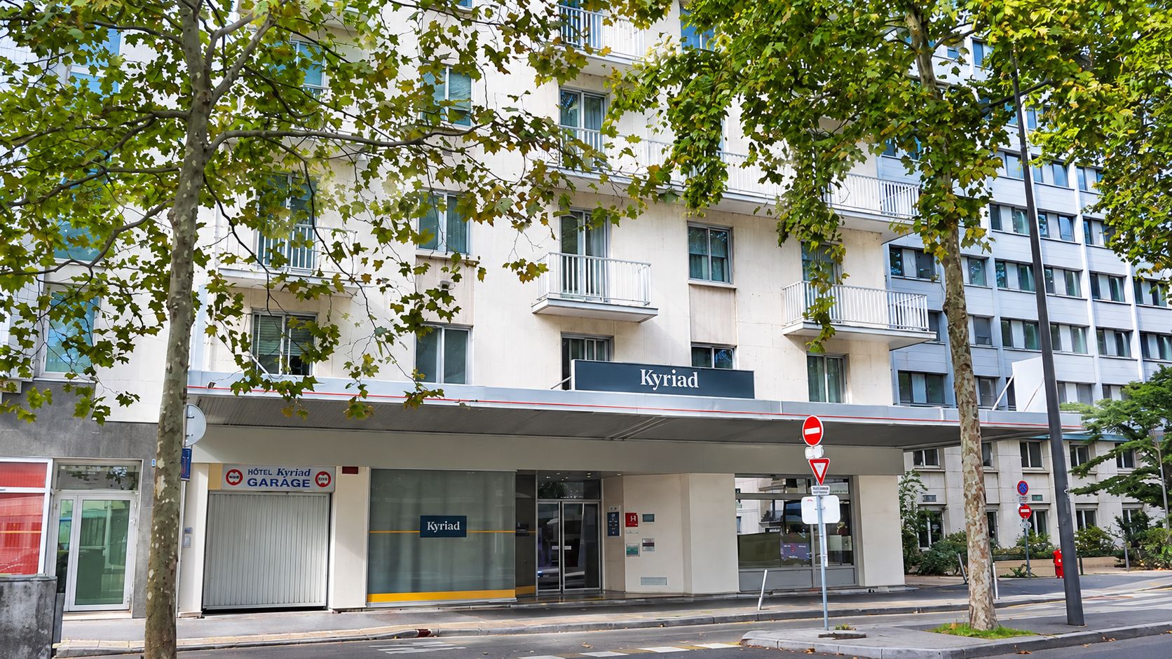 A hotel named 'Kyriad' with a garage sign, a no entry sign, and a no parking sign.