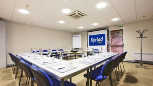 A conference room with a long table, blue chairs, water bottles, and a presentation screen displaying "Kyriad Hotel". - Kyriad - Tours Centre (Tours)