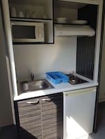 Una kitchenette compacta con microondas, estufa, pileta y alacenas.