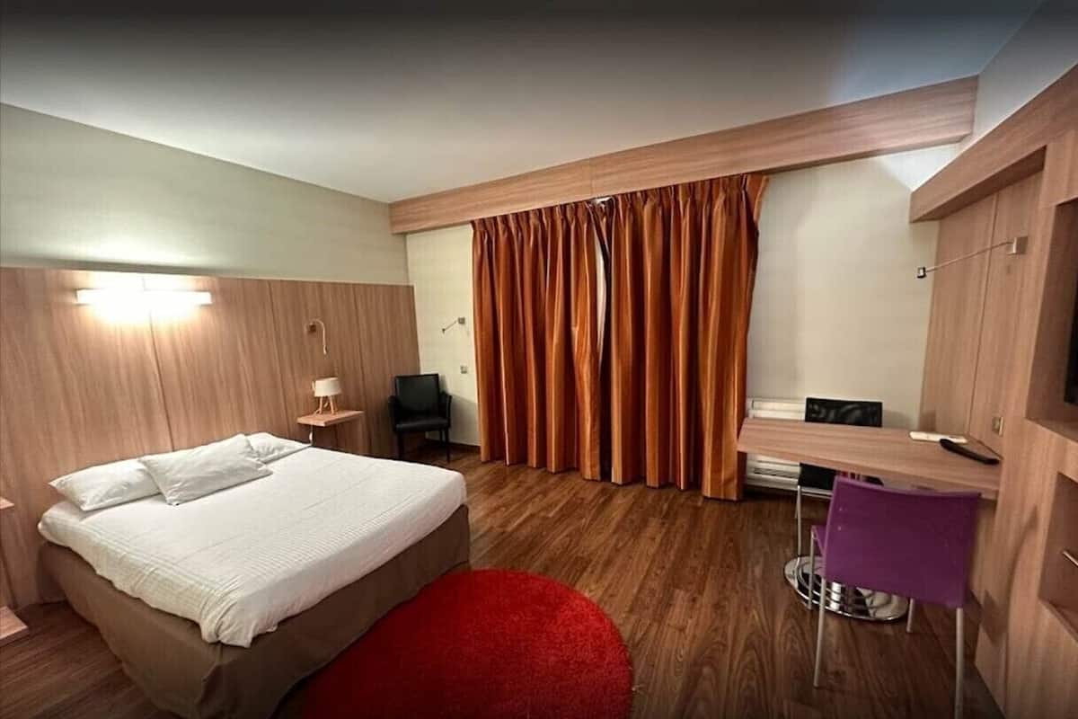 Una habitación de hotel moderna con cama, escritorio, silla y armario.