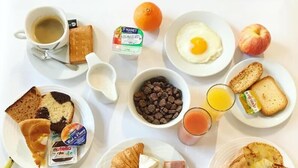 A breakfast table with various food items and a newspaper.