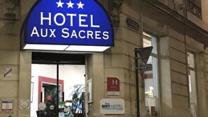 A hotel entrance with a blue sign reading "HOTEL AUX SACRES."