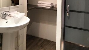 A bathroom with a white sink, a mirror, a towel rack, and a glass shower door.