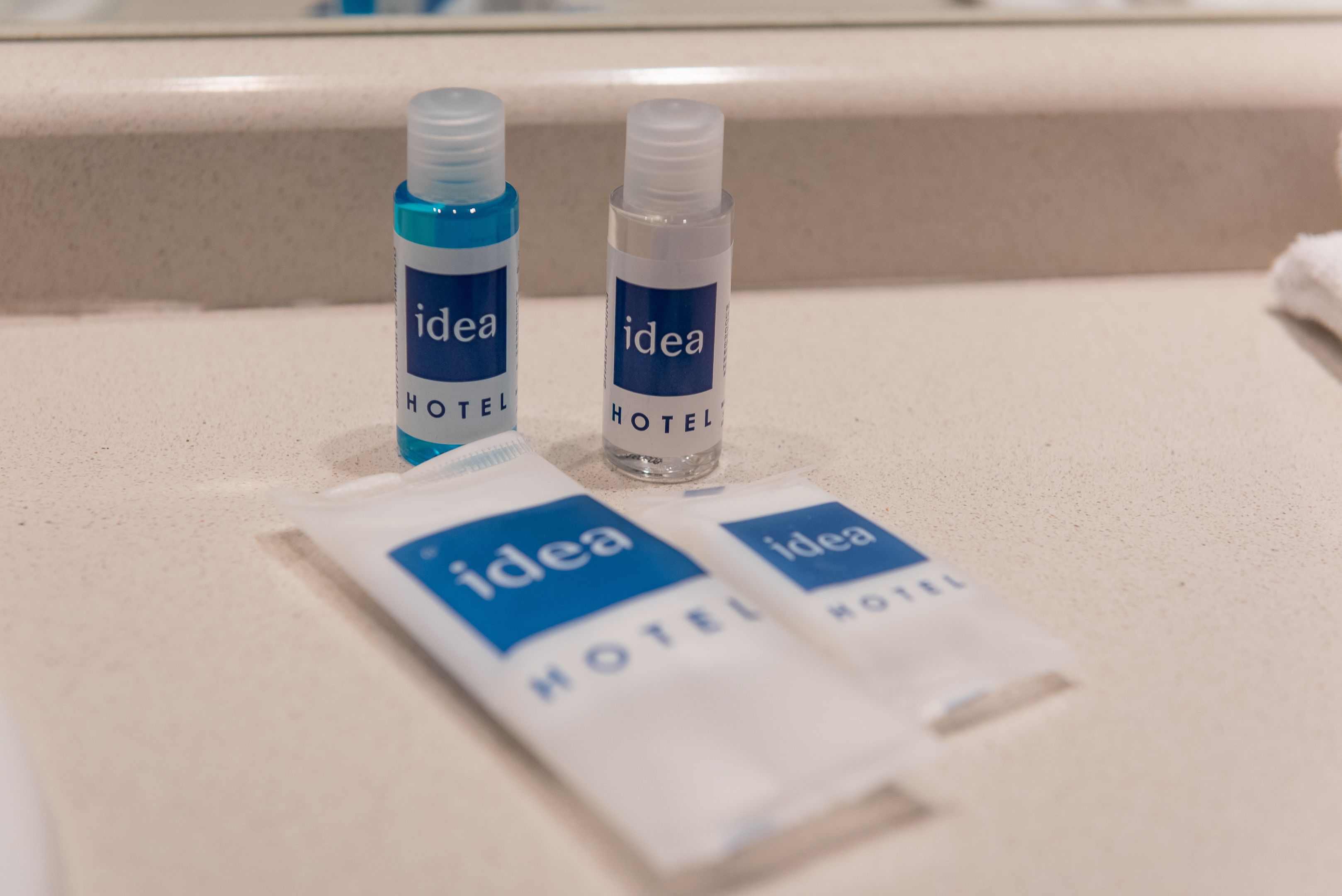 Dos botellas y dos paquetes con la etiqueta 'idea HOTEL' sobre una encimera.