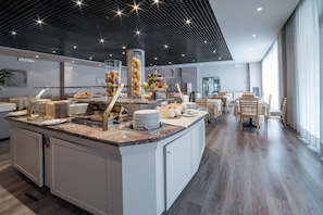 Een moderne ontbijtruimte met een centraal eiland, een buffetopstelling en een zithoek.