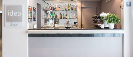 A bar area with a counter, shelves of liquor bottles, a potted plant, and a sign that reads "idea bar".