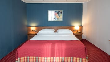 A hotel room with a large bed, two bedside lamps, a nightstand, and a wall-mounted picture.