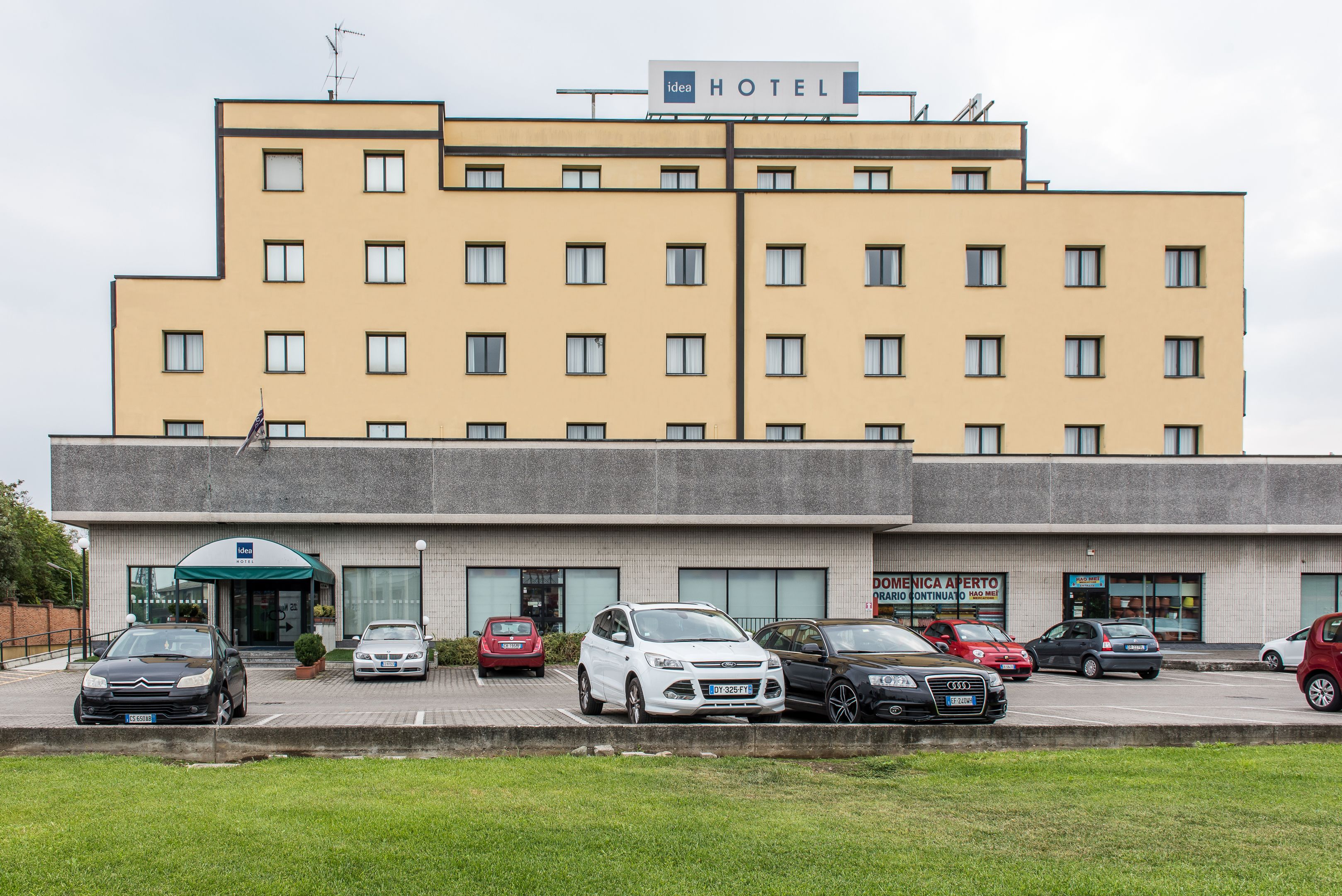 A hotel with multiple floors, a parking lot with several cars, and a sign indicating it is a hotel.