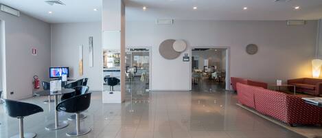 A modern lobby with a reception desk, black and red seating, and a television.
