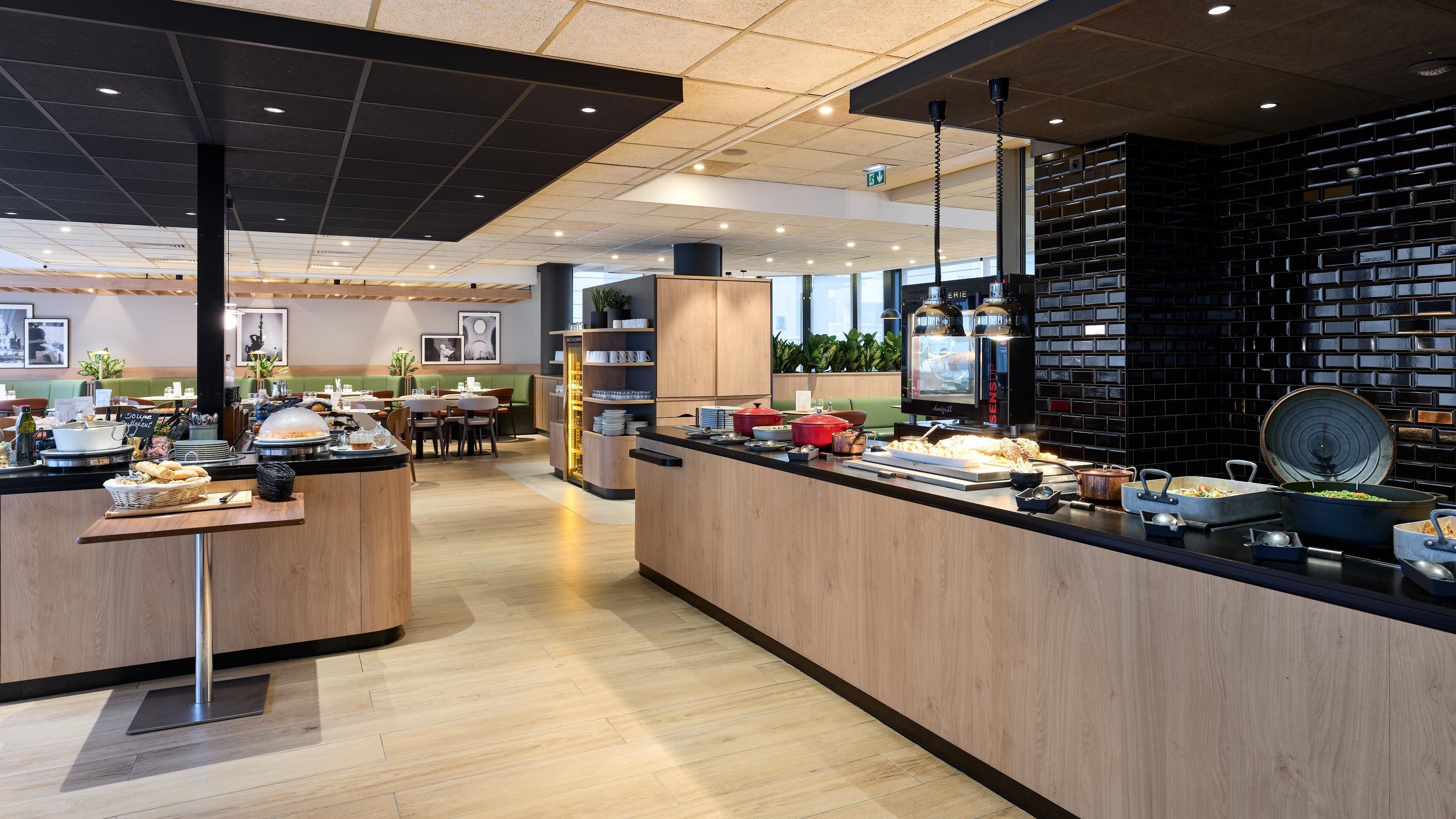 A modern restaurant with a buffet setup, wooden furniture, and a brick accent wall.
