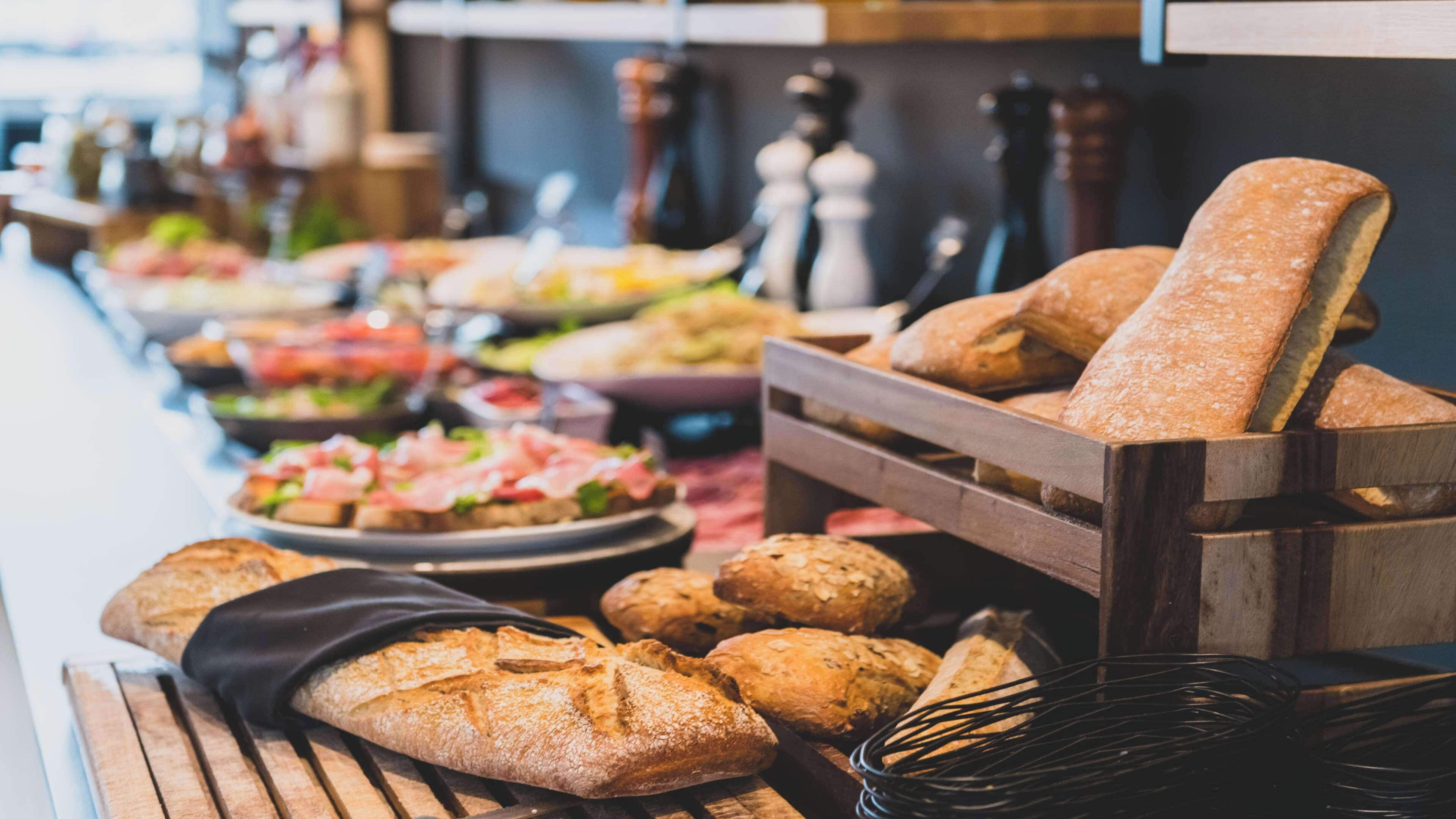 A buffet table with various breads and dishes.