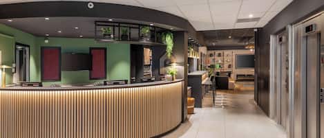 A modern reception area with a curved counter, green walls, and a visible elevator.