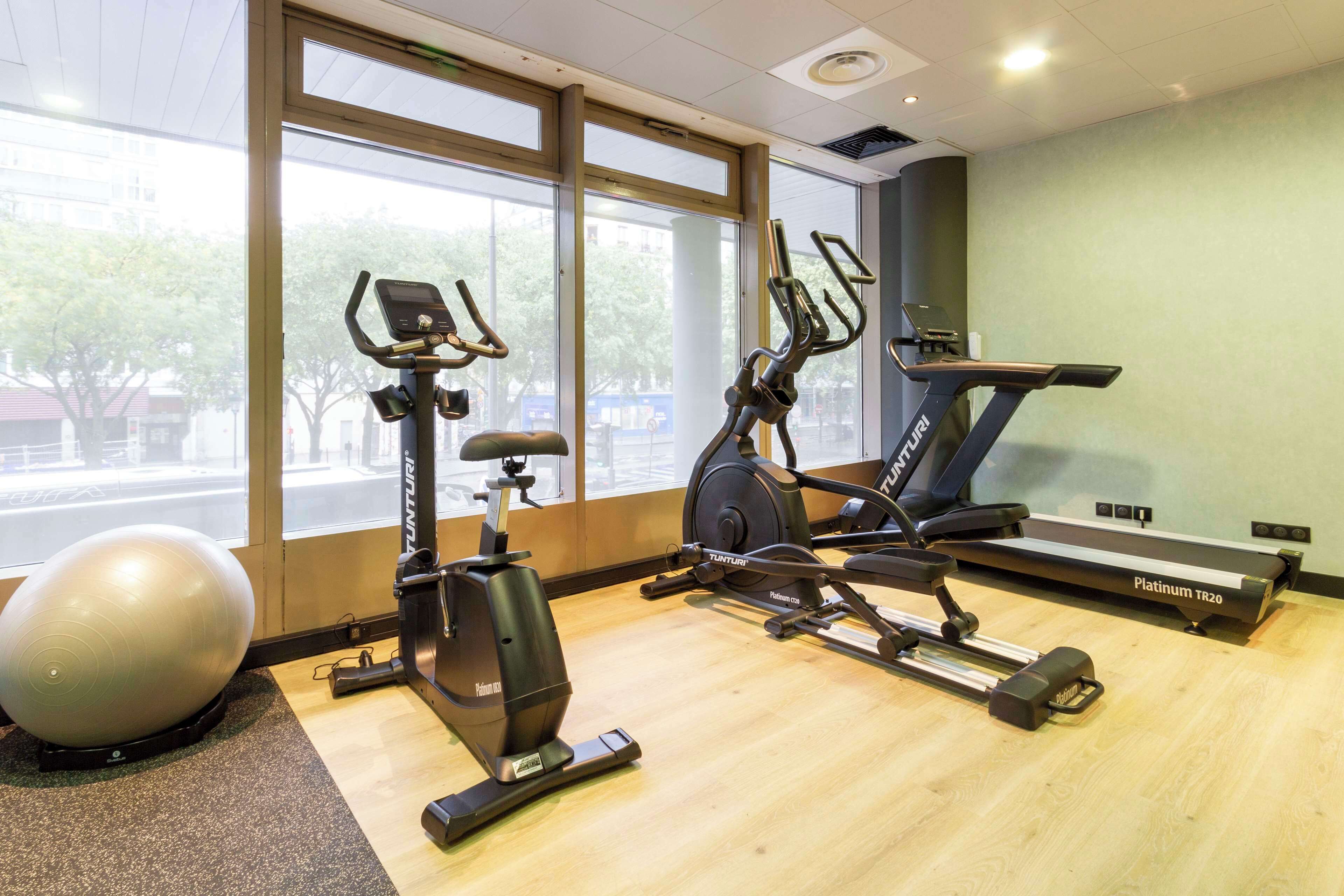 A gym with a stationary bike, elliptical, treadmill, and a large exercise ball.
