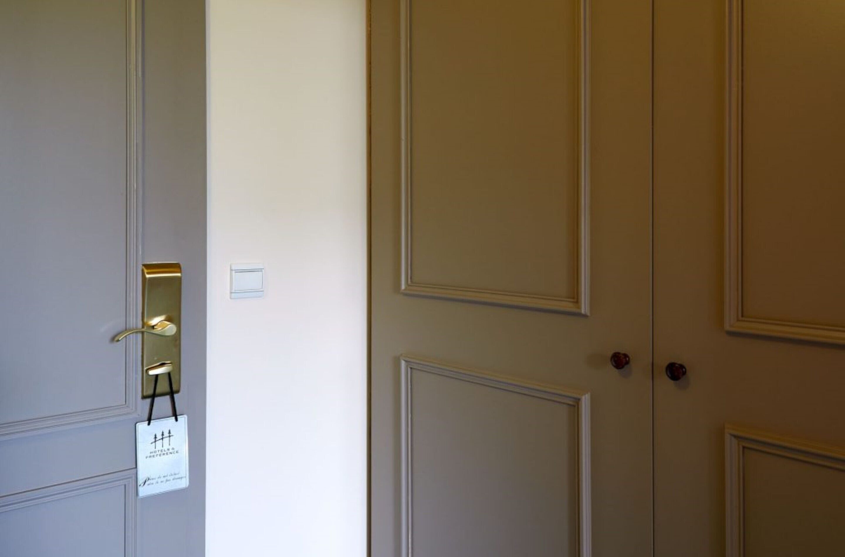 A closed door with a brass handle and a small sign hanging on the door.
