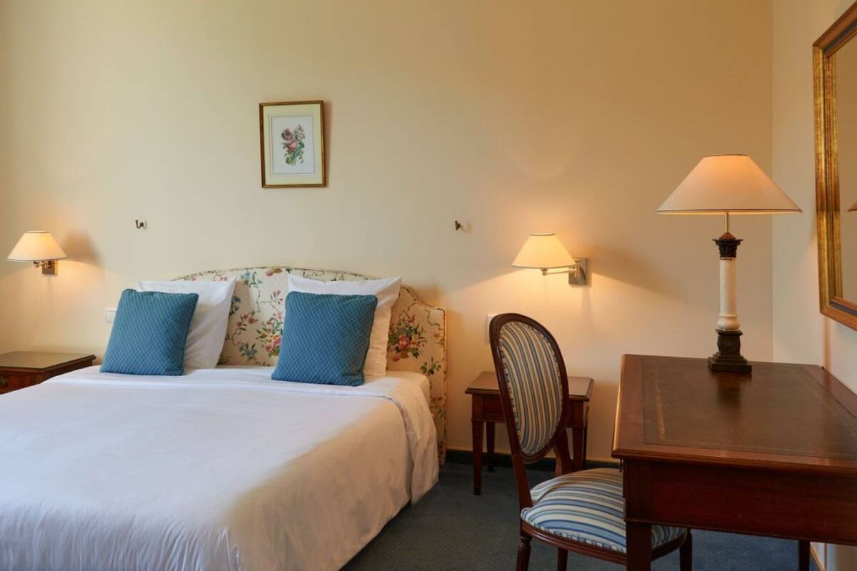 Une chambre d’hôtel comprenant un lit, deux tables de chevet, une chaise et un bureau.