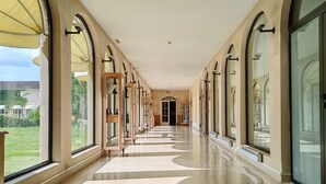 A long corridor with arched windows and a tiled floor. - Relais de Margaux – Hôtel, Golf & Spa (Margaux-Cantenac)