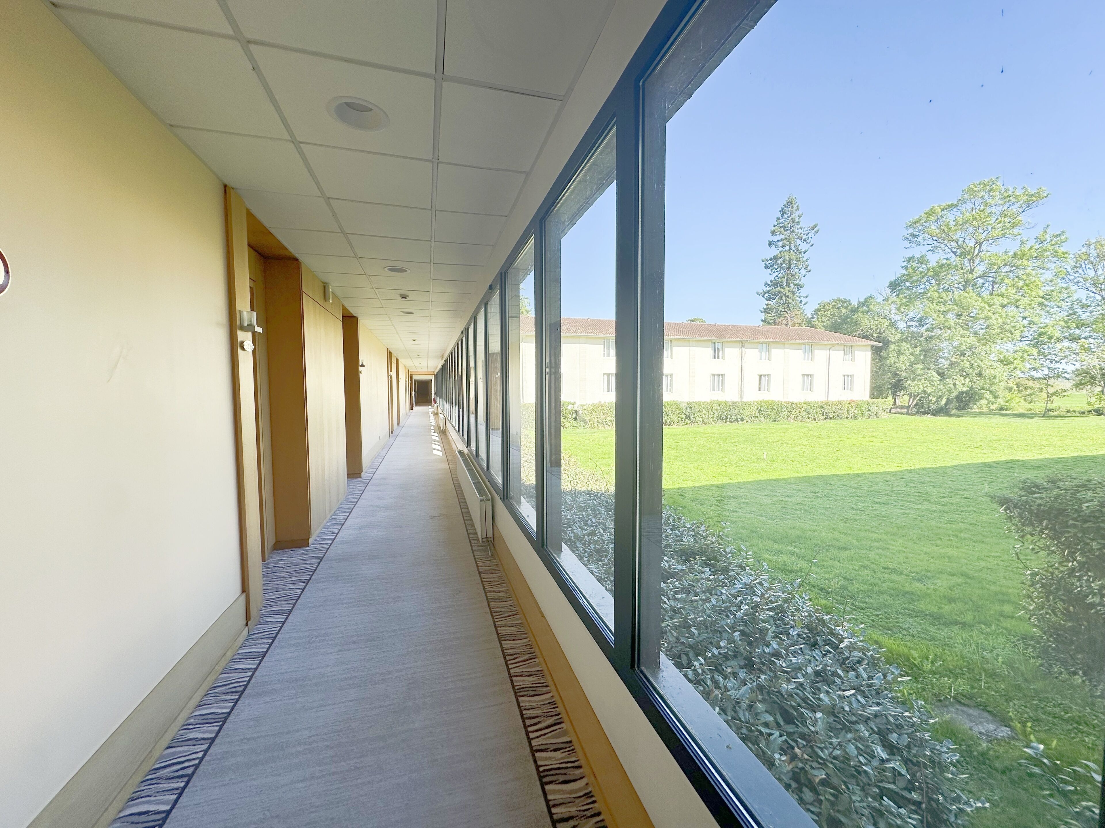 A long hallway with a carpeted floor and a large window on one side.