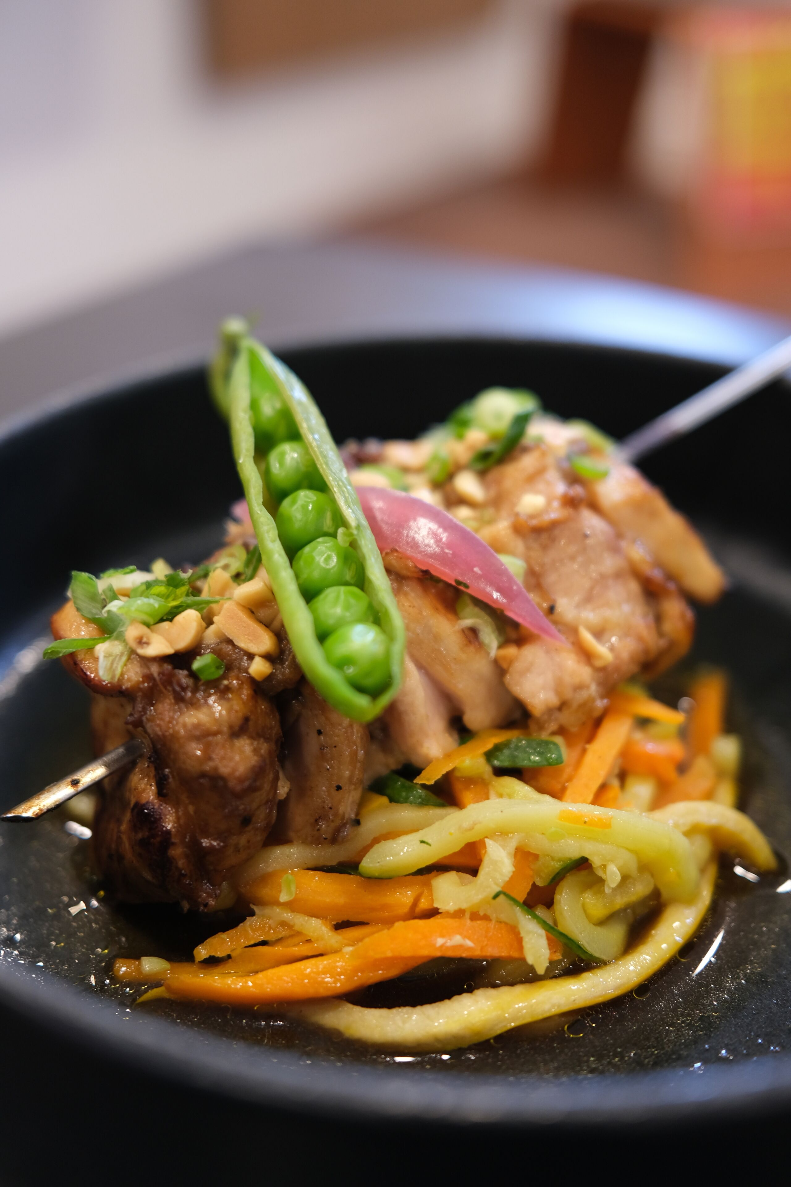 A dish with meat, green peas, and carrots.